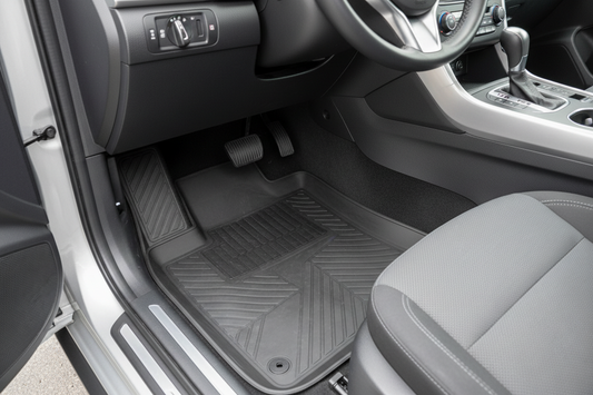 Clean modern car footwell with fitted all-weather floor mats, realistic rubber texture, soft daylight, tidy pedals, and practical everyday interior protection mood. No people, no text, no logo.